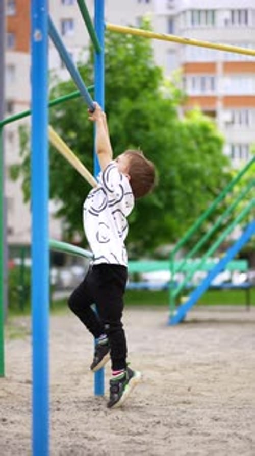 Young boy stands on his toes trying to reach the horizontal bar.