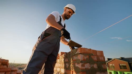 Caucasian and Indian Builders Laying Bricks on Cottage Construction
