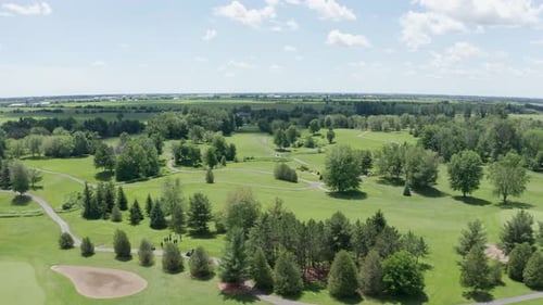Aerial view of golf course, fairways, tee boxes, sand traps, greens and carts on path before tournam