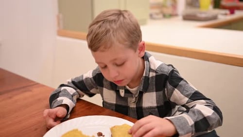 Child Eats a Taco at a Wooden Table