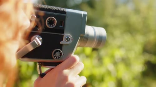 Young Woman Filming with Vintage Movie Camera