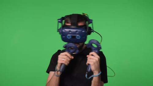 A Man Uses Virtual Reality Glasses to Play in a Studio on a Green Background