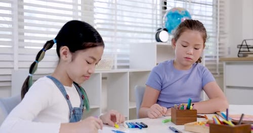 Asiatisches Mädchen im Teenageralter zeichnet während des Kunststudiums im Klassenzimmer mit gelbem Stift auf ein Notizbuch, Grundschule