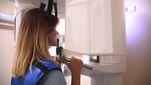 Schöne Frau, die sich morgens in einer modernen Klinik zur Mundgesundheitsuntersuchung einer zahnärztlichen Röntgenuntersuchung unterzieht