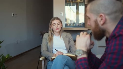 Woman Listens and Takes Notes During Conversation