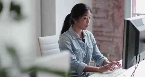 Young adult female working in an office on a desktop computer