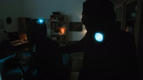 People in Dark Clothes and Headlamps in Living Room