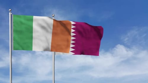 Ireland and Qatar Flags Waving Against a Clear Blue Sky