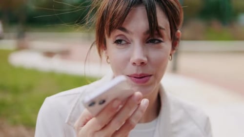 Close up of the Woman Leaves Cheerful Voice Message in Park