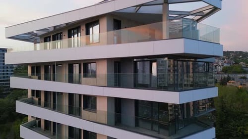 Drohnenaufnahme einer modernen Wohngebäudefassade mit beigen Paneelen und weißen Balkonen