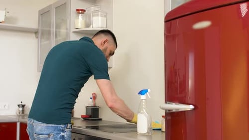 Man Cleaning Kitchen Counter with Spray and Cloth
