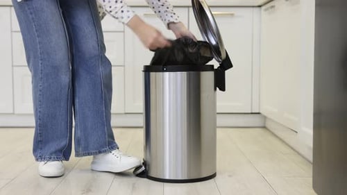 Woman Disposing of Trash in Kitchen Recycling Bin