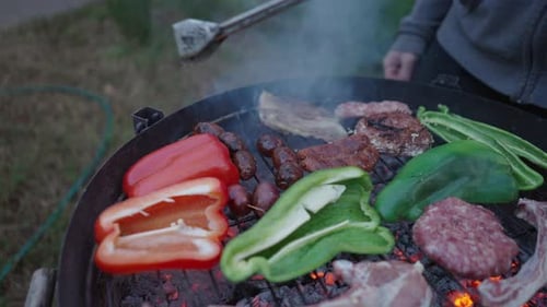 Nicht wiederzuerkennender Mann, der verschiedene Fleischsorten kocht, Würste umdreht, Zeitlupenschuss