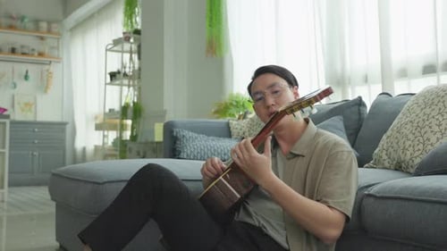 Man Playing Guitar on Floor in Living Room