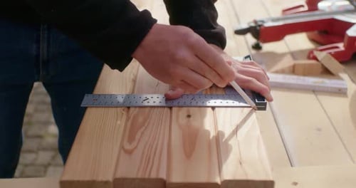 Hands Measuring and Marking Wood with Pencil and Ruler