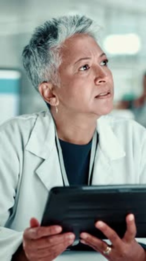 Woman in Lab Coat Uses Tablet in Hospital