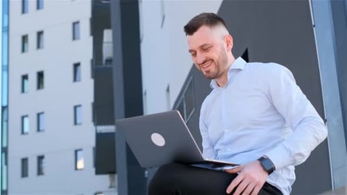 Portrait of Stylish Hispanic Businessman Working on Laptop Near Business Center