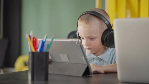 Baby Boy is Viewing Educational and Developmental Cartoon on Tablet Screen Listening By Headphone
