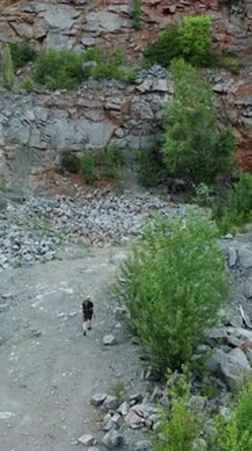 Traveler with a backpack is walking near the river on the stone background in summer.