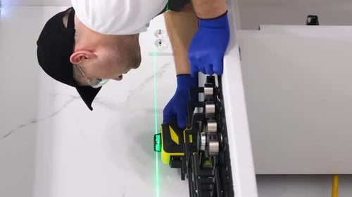 The Process of Installing Furniture in the Kitchen Using a Construction Laser Leveler Vertical Video