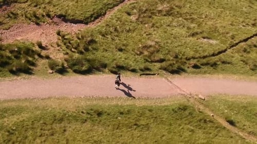 Hikers on Dirt Path in Rural Grassy Hills