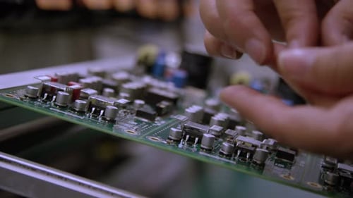 Electronics manufacturing - Macro close up side angle of circuit board being built by hand