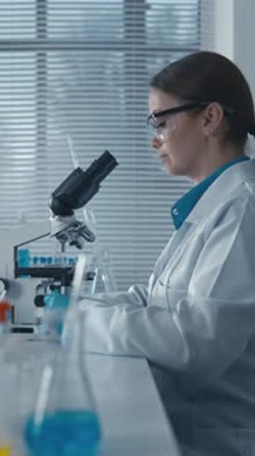 Focused Scientist Uses Microscope in Bright Lab