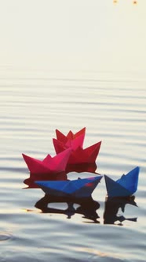 Paper Boats Floating on Water at Sunrise or Sunset