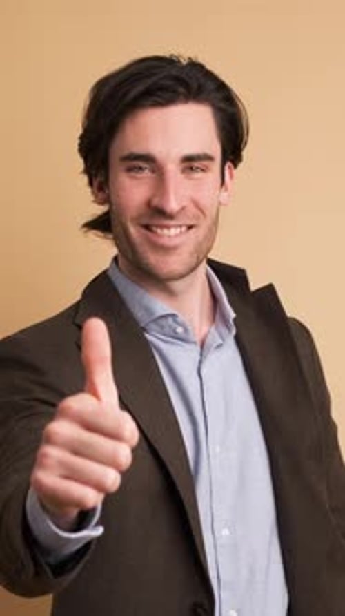 Happy Businessman Showing Thumbs Up in Brown Studio