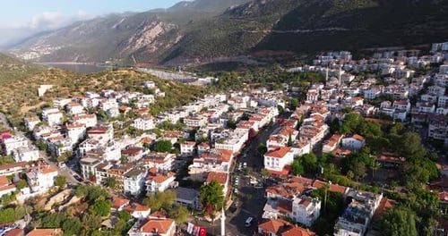 Aerial dolly of Kas in Antalya, Turkey, tiled roofs and white facades nestled in green hills, boats