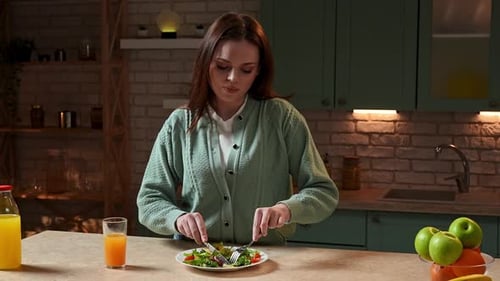 Young Adult Woman Eating a Salad in Kitchen