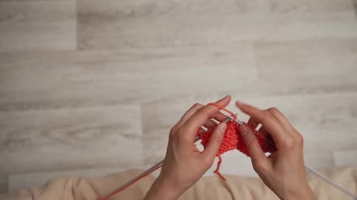 Hands Knitting Orange Wool in Home Setting