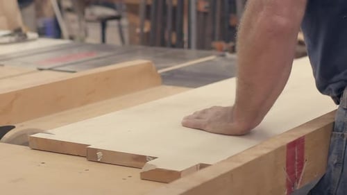 Un artisan coupe des planches de bois sur une table, une scie dans un bûcher au ralenti