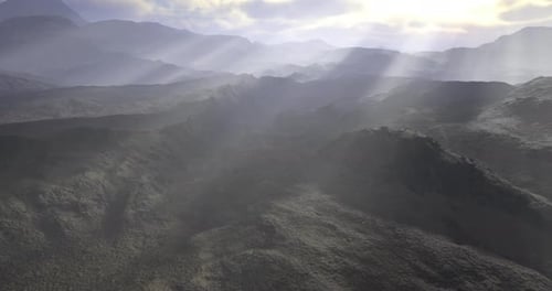 La lumière du soleil traverse les nuages au-dessus d'un paysage montagneux à l'aube