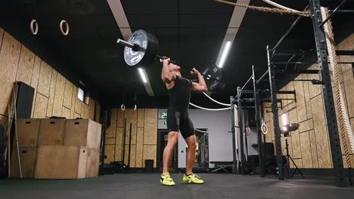 The training process. Athletic man performing weightlifting exercises with a barbell in a gym.