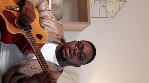 Man Plays Acoustic Guitar in Home Setting