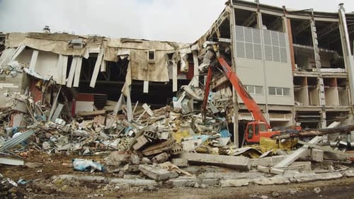 Red Excavator Disassembles Debris Rubble of Hockey Stadium