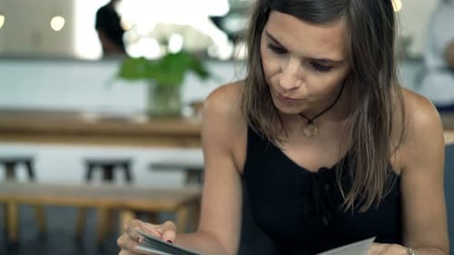 Young woman at cafe reading menu and placing order with friendly waiter