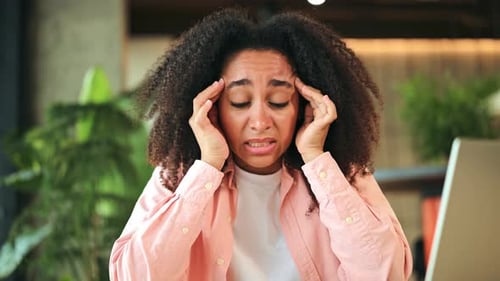 Stressed Woman Experiencing a Severe Headache and Migraine in Modern Office