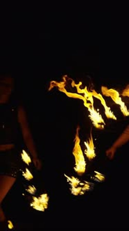 Dynamic Fire Performance at Night with Swirling Flames and Silhouetted Performer Creating Dramatic