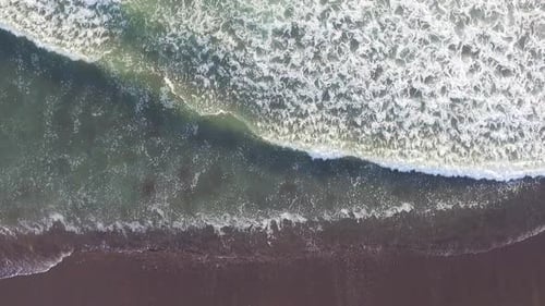 Aerial View of Crashing Waves on a Dark Sandy Beach