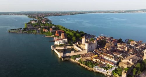 Aerial View Of Castello Scaligero At Sunrise On Lago di Garda In Sirmione, Italy. tilt-down shot