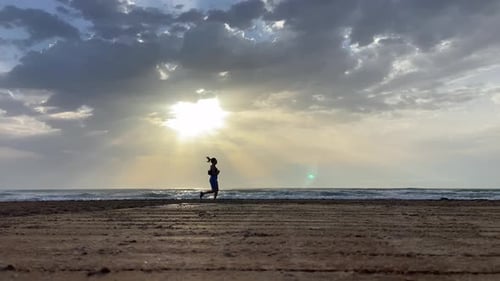 Sporty female running along the beach alone at sunset. Values of effort