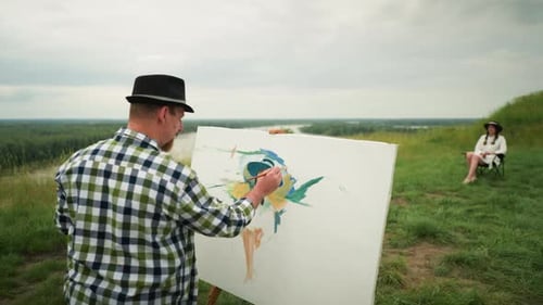 Painter Paints a Model on a Green Hillside