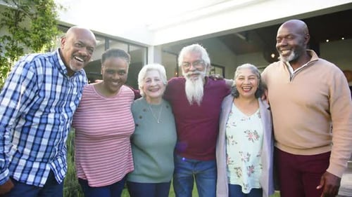 Portrait of happy diverse female and male senior friends embracing in sunny garden, slow motion