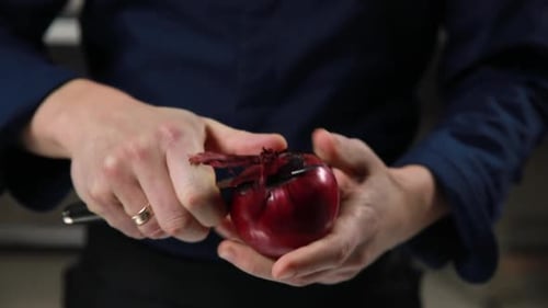 Person peeling a Red Onion with Knife