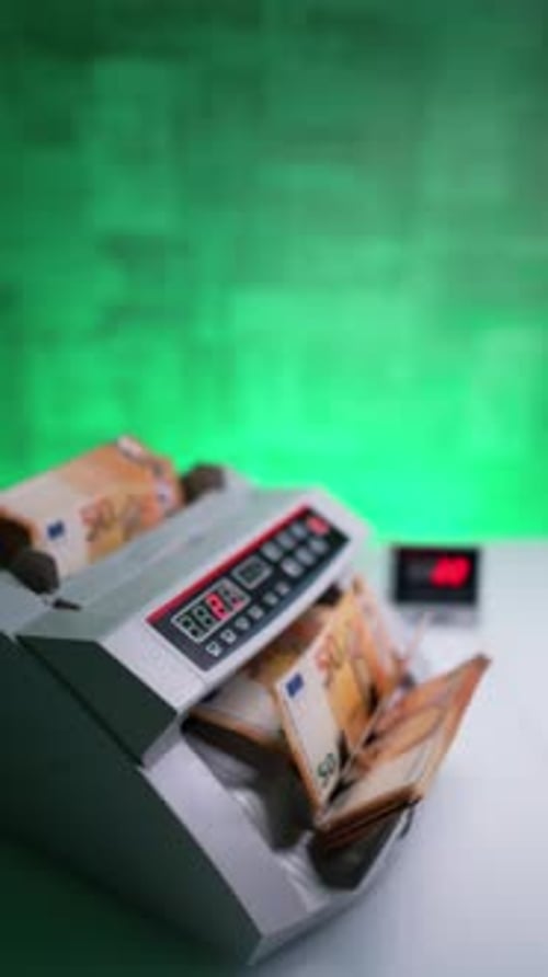Money counting machine processing fifty euro banknotes. Display shows the number of bills.