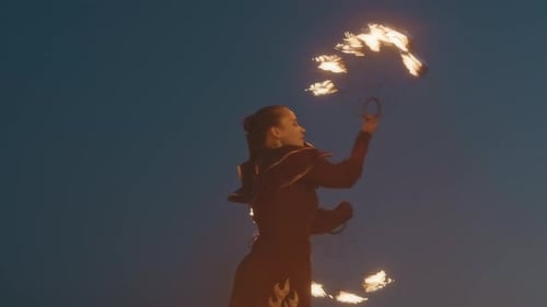 Woman Fire Dancing with Flaming Torches at Night