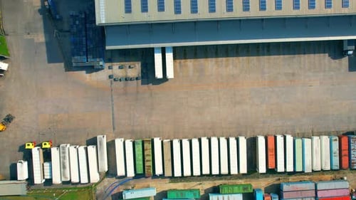 Drohne fliegt über viele Frachtcontainer und Sattelschlepper