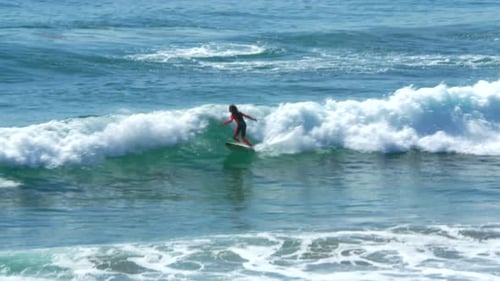 Surfing in huntington beach California waves under a sunny blue sky drone view